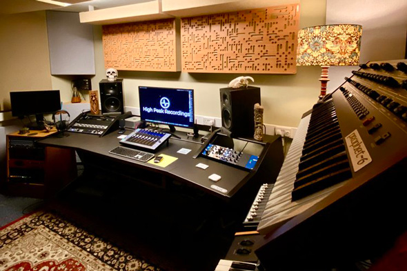 music studio with recording equipment and keyboards featuring a cozy lamp and decorative wall panels suitable for 2 music production styles