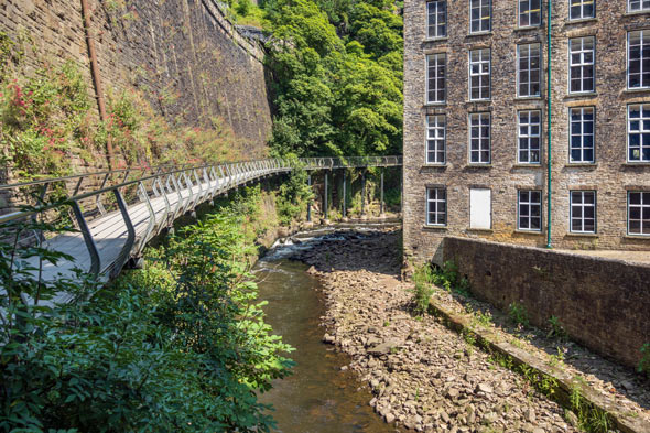 bridge over a river with lush greenery and an industrial building four seasons nature landscape